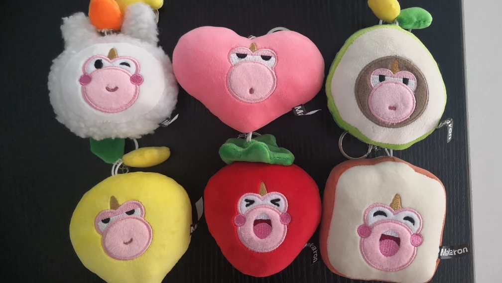 Assortment of custom plush keychains and plush bag charms clipped to a handbag and a backpack