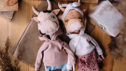 A lineup of highly detailed custom character plush dolls on a factory inspection table, showing consistent facial embroidery and hair structures.