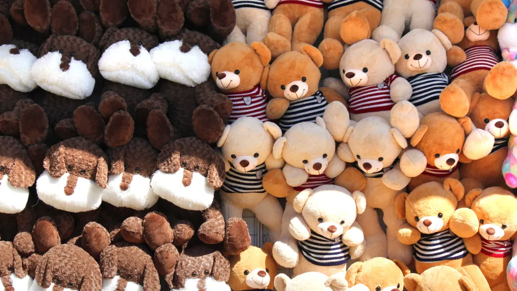 A lineup of 20cm custom mascot plush toys wearing team jerseys on a factory inspection table